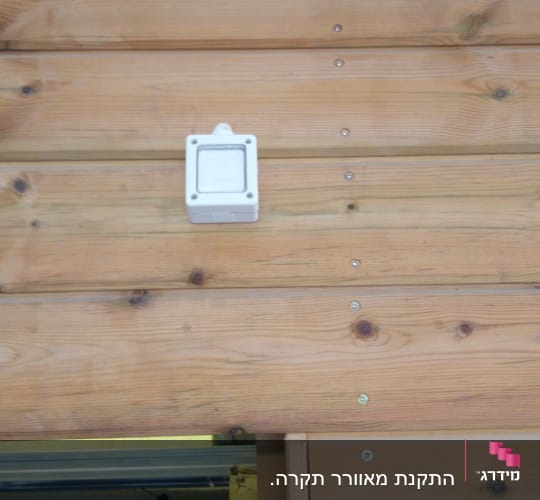 קופסת חיבורים חשמלית מותקנת על קיר עץ